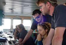 L'équipe scientifique (le commandant, le chef de mission et Anouk ODY) étudient les dernières photos satellites pour diriger le navire sur les zones de présence de signal
© Hubert BATAILLE